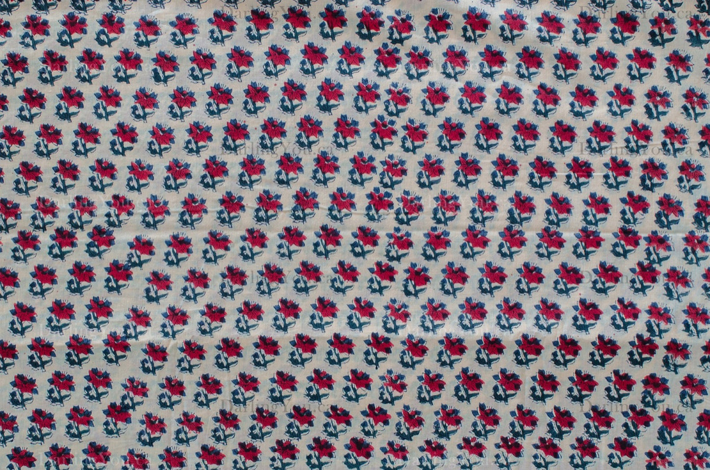 White cotton fabric featuring red and blue floral hand block print, made using traditional artisan techniques in Jaipur, India.