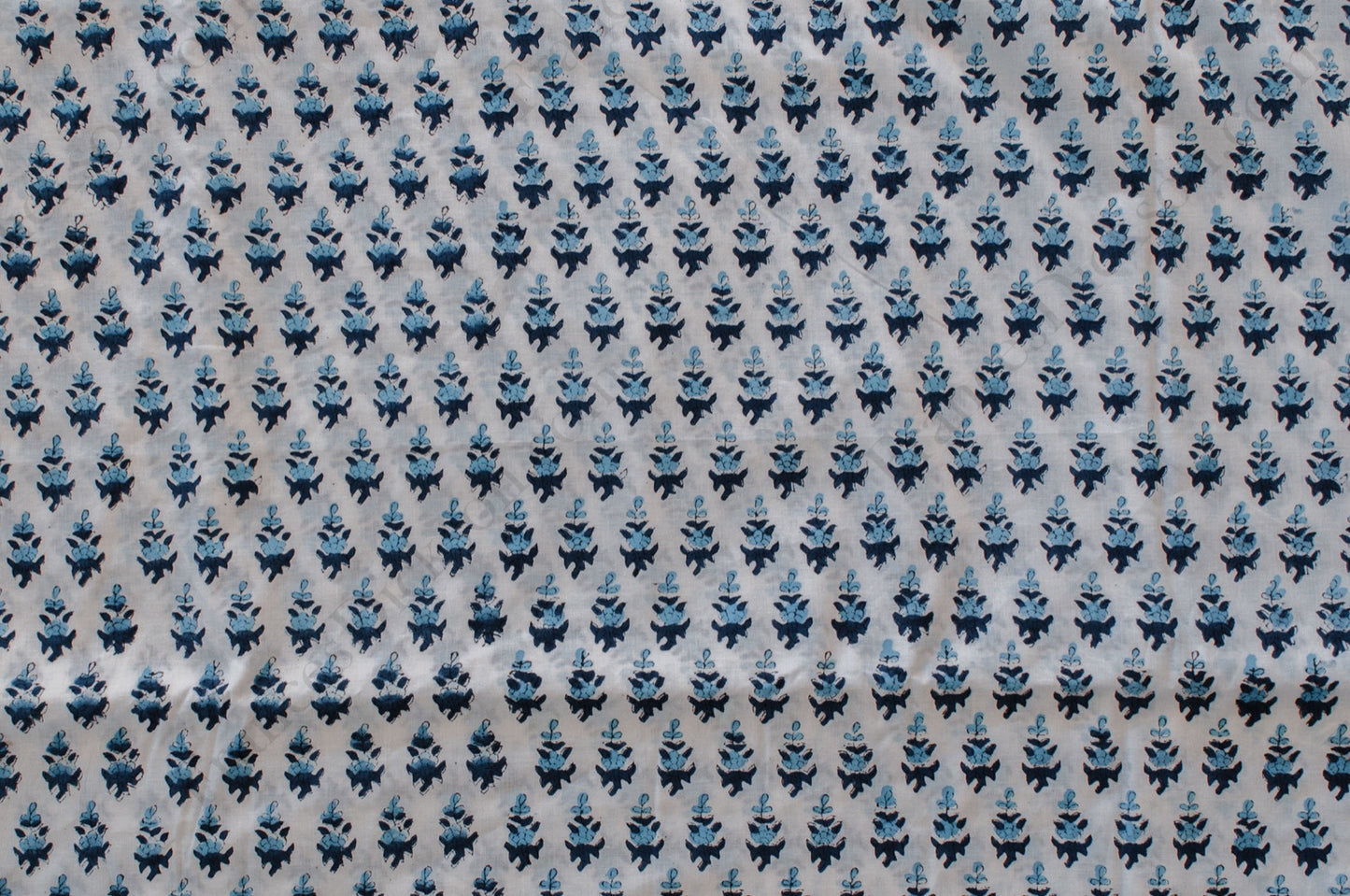 White cotton fabric with two-tone blue floral hand block print, handcrafted in Jaipur, India using traditional woodblock techniques.