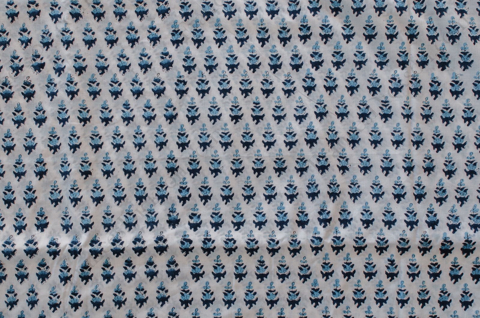 White cotton fabric with two-tone blue floral hand block print, handcrafted in Jaipur, India using traditional woodblock techniques.