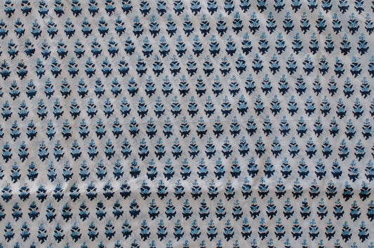 White cotton fabric with two-tone blue floral hand block print, handcrafted in Jaipur, India using traditional woodblock techniques.