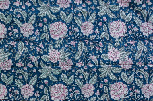 Blue cotton fabric with hand block printed pink blossoms and green leaves, crafted by artisans in Jaipur, India using traditional methods.