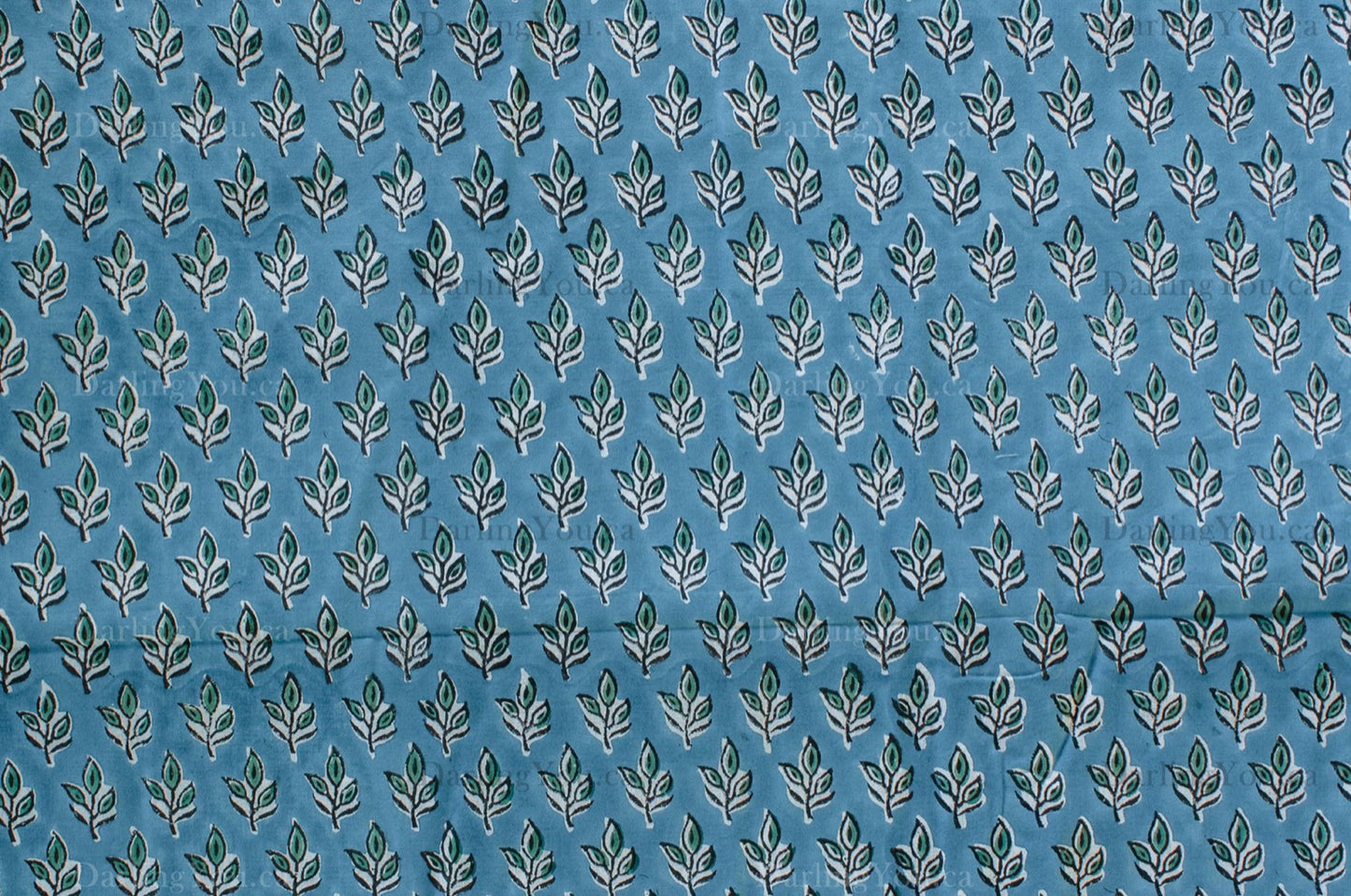 Blue cotton fabric with green floral block print and white accents, handmade in Jaipur, India using traditional artisan techniques.