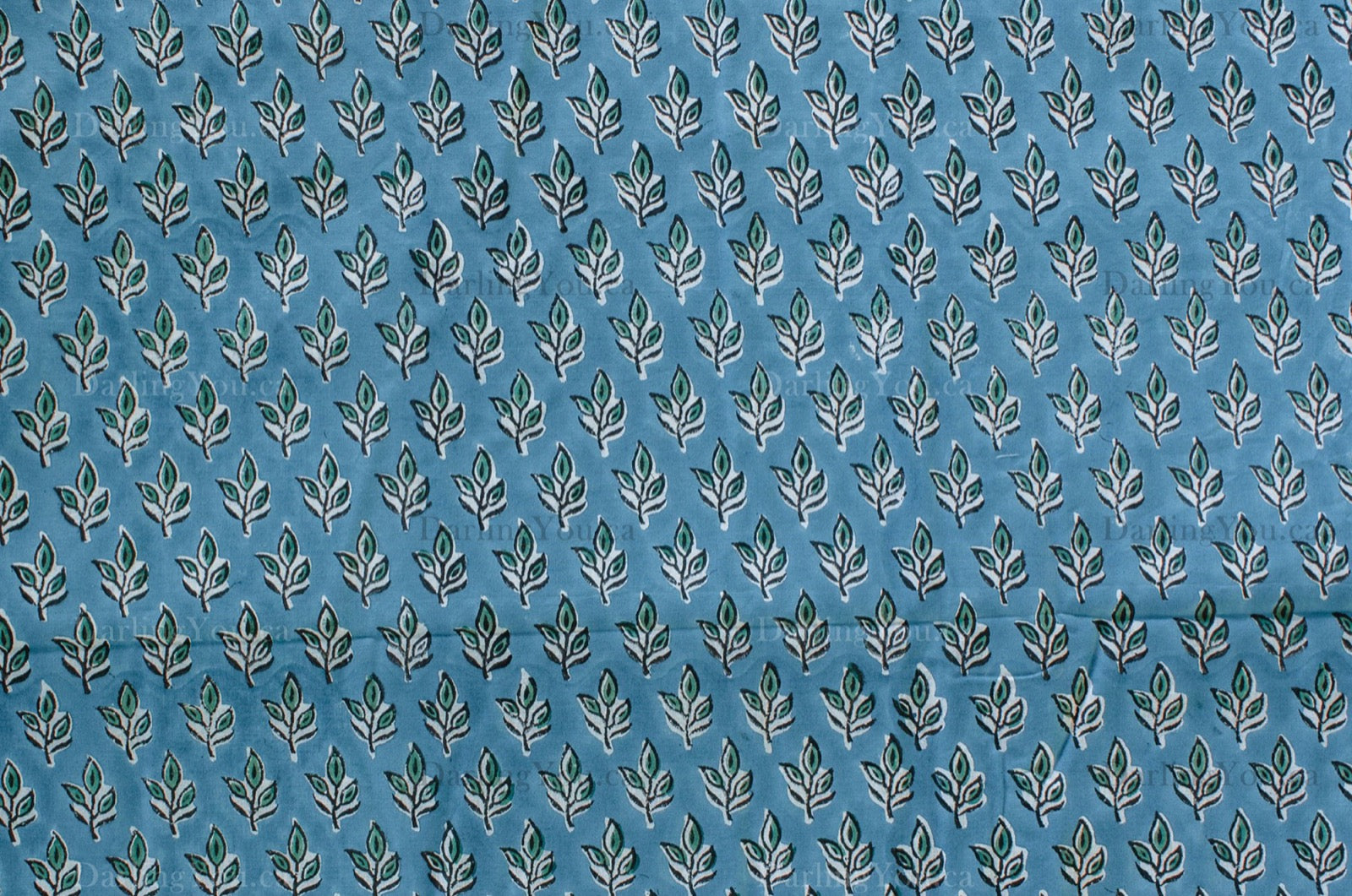 Blue cotton fabric with green floral block print and white accents, handmade in Jaipur, India using traditional artisan techniques.