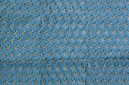 Blue cotton fabric with green floral block print and white accents, handmade in Jaipur, India using traditional artisan techniques.
