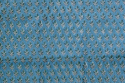 Blue cotton fabric with green floral block print and white accents, handmade in Jaipur, India using traditional artisan techniques.