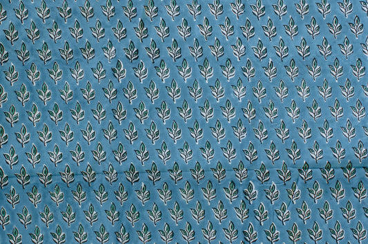 Blue cotton fabric with green floral block print and white accents, handmade in Jaipur, India using traditional artisan techniques.