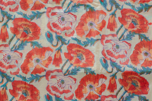 White cotton fabric hand block printed with orange, red, and blue floral motifs, handcrafted by artisans in Jaipur, India.