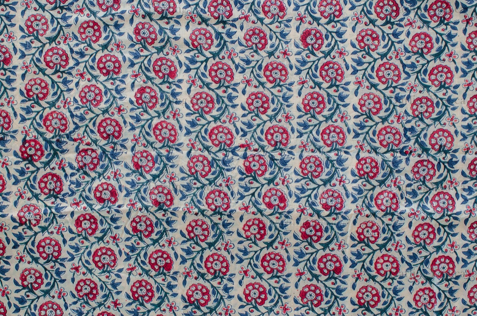 Hand block printed cotton fabric featuring a red, blue, and green floral motif on white, made by artisans in Jaipur, India.