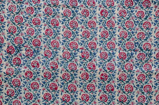 Hand block printed cotton fabric featuring a red, blue, and green floral motif on white, made by artisans in Jaipur, India.