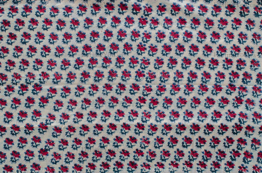 White cotton fabric featuring red and blue floral hand block print, made using traditional artisan techniques in Jaipur, India.