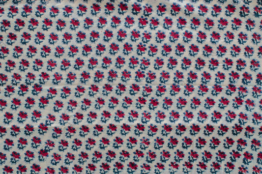 White cotton fabric featuring red and blue floral hand block print, made using traditional artisan techniques in Jaipur, India.