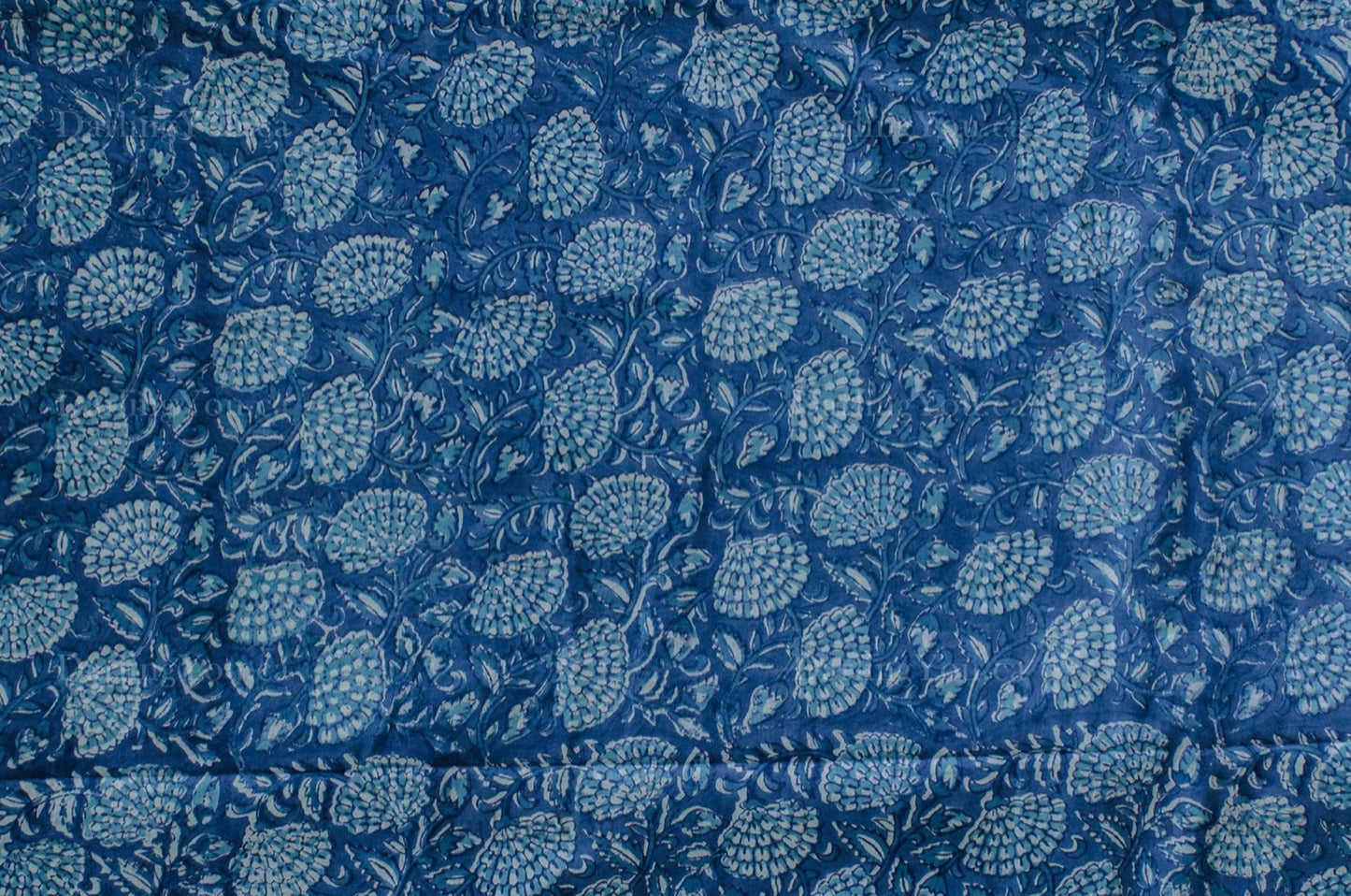 Blue and white cotton fabric with dense floral block print, handcrafted using traditional techniques in Jaipur, India.