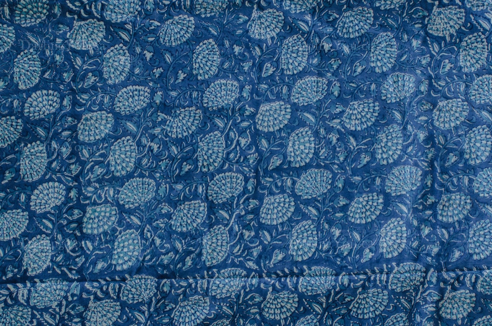 Blue and white cotton fabric with dense floral block print, handcrafted using traditional techniques in Jaipur, India.