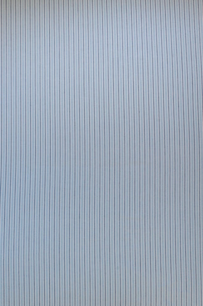 Organic yarn-dyed cotton fabric with fine pale blue stripes and navy woven detailing in a lightweight shirting weave.