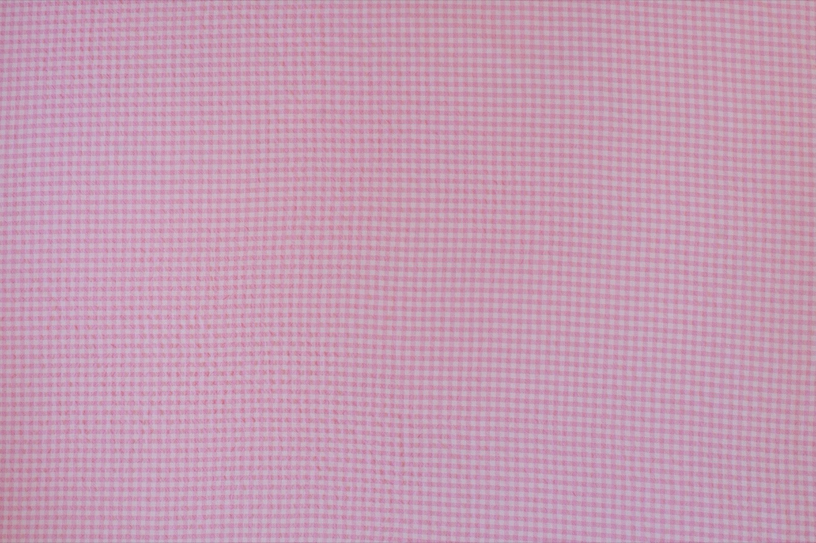 Organic yarn-dyed cotton seersucker fabric featuring candy pink micro gingham check with lightweight puckered texture.