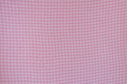 Organic yarn-dyed cotton seersucker fabric featuring candy pink micro gingham check with lightweight puckered texture.