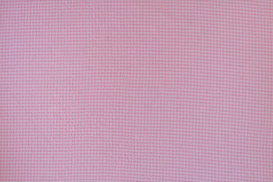 Organic yarn-dyed cotton seersucker fabric featuring candy pink micro gingham check with lightweight puckered texture.