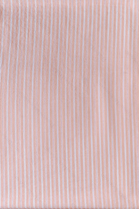 Peach organic cotton shirting fabric with white yarn-dyed stripes and ladder embroidery detail, folded to show texture and weave.