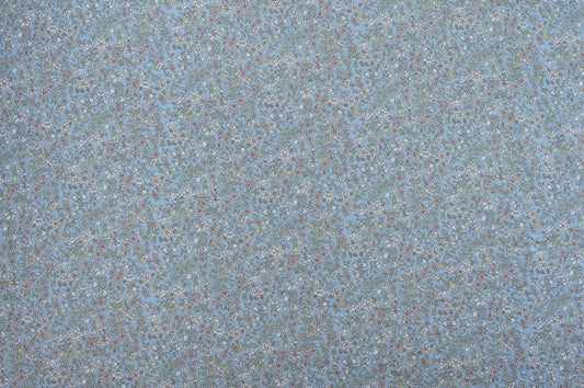 Organic cotton fabric with dense floral print on pale blue background featuring vintage-inspired botanical pattern.