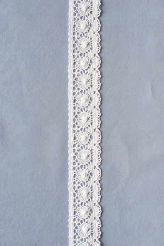 Off-white cotton lace with repeating circular medallion motifs and scalloped edges, showing intricate openwork pattern.