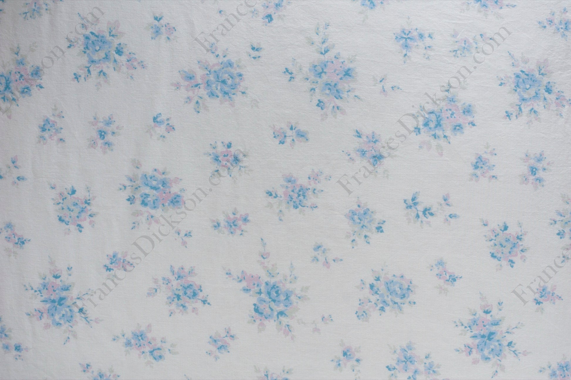 Organic cotton cambric fabric with scattered powder blue and blush pink floral bouquets on an ivory background, shown flat and draped on a dress form.